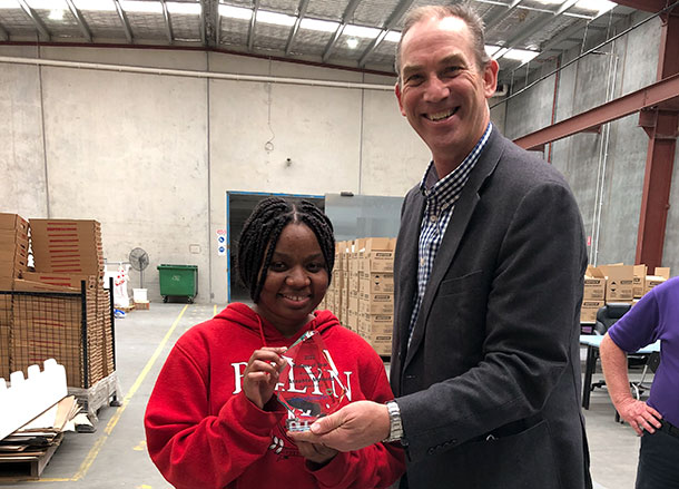 Assunta is smiling, she is being handed her glass award trophy by the Mambourin CEO