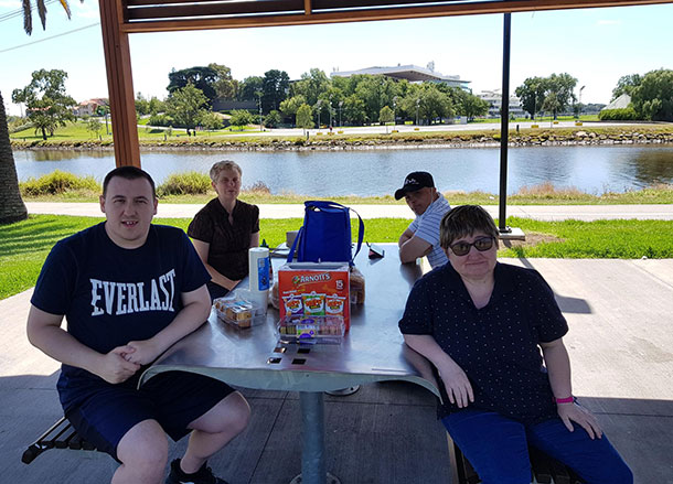 Four people sit around outdoor picnic tables