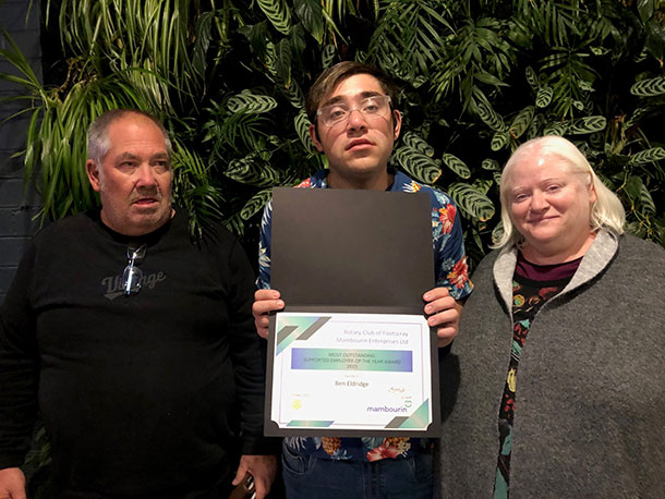 Ben stands holding his certificate alongside his family