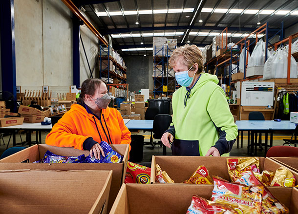 Two women in high vis vests chat at a work station