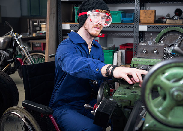 A mechanic in a wheelchair working on a vehicle