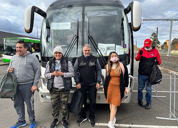 Five people stand outside in front of a bus