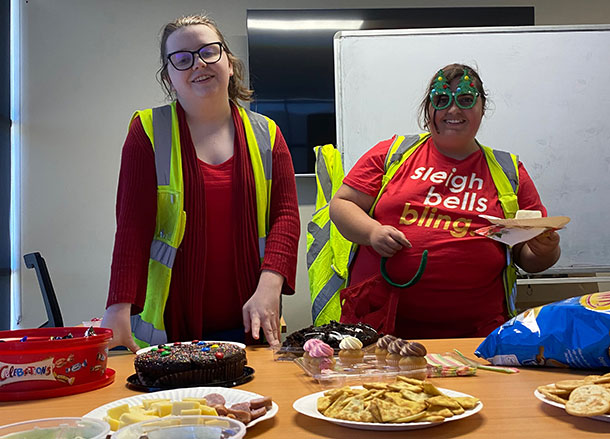 Caitlin and Keyannah are standing in front of a table with plates of party food on it