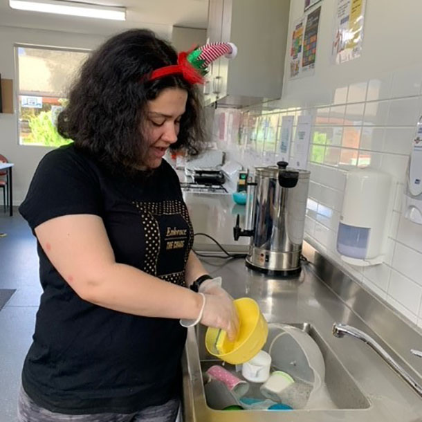 Carla is standing at a sink washing dishes