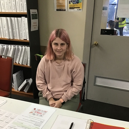 Chloe is sitting in front of a table in a classroom