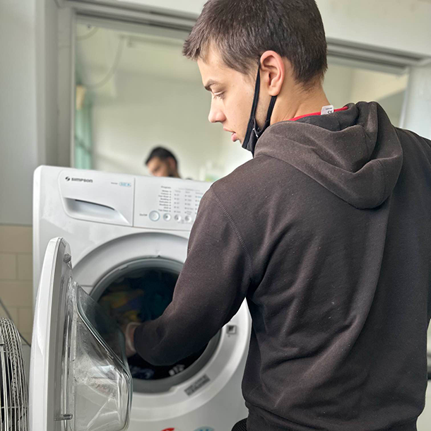 A man puts laundry in a washing machine