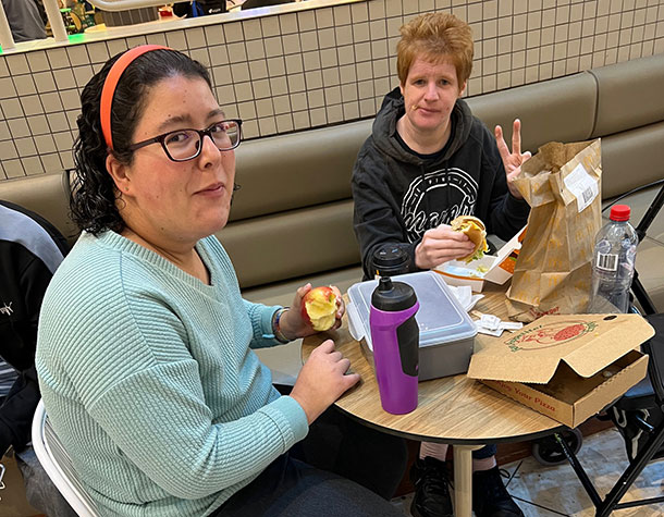 Two people sit at a table in a food court having lunch