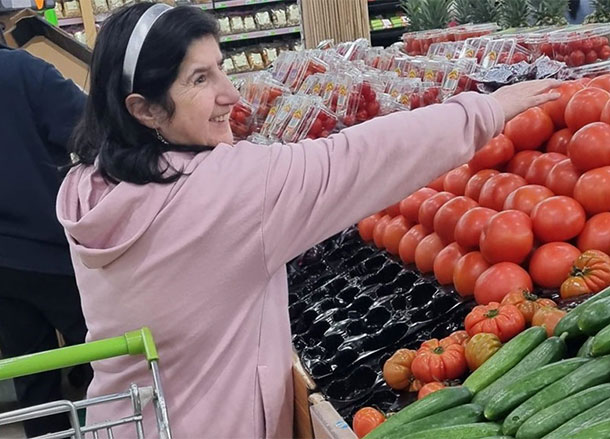 A woman selects a tomato from the fresh food display in a supermarket