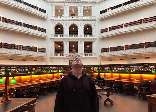 Hamish stands in the State Library looking up towards the very high ceiling