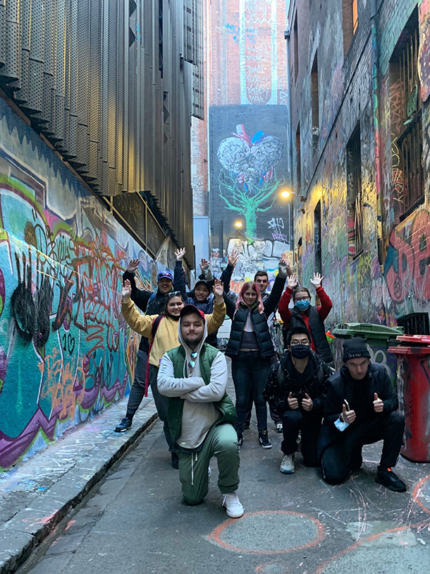 A group of people pose in a laneway covered in street art