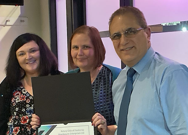 Cassandra, Judy and Emanuel stand in a row smiling, Judy is holding her certificate