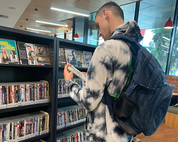 A SLES participant is browsing DVDs in a library