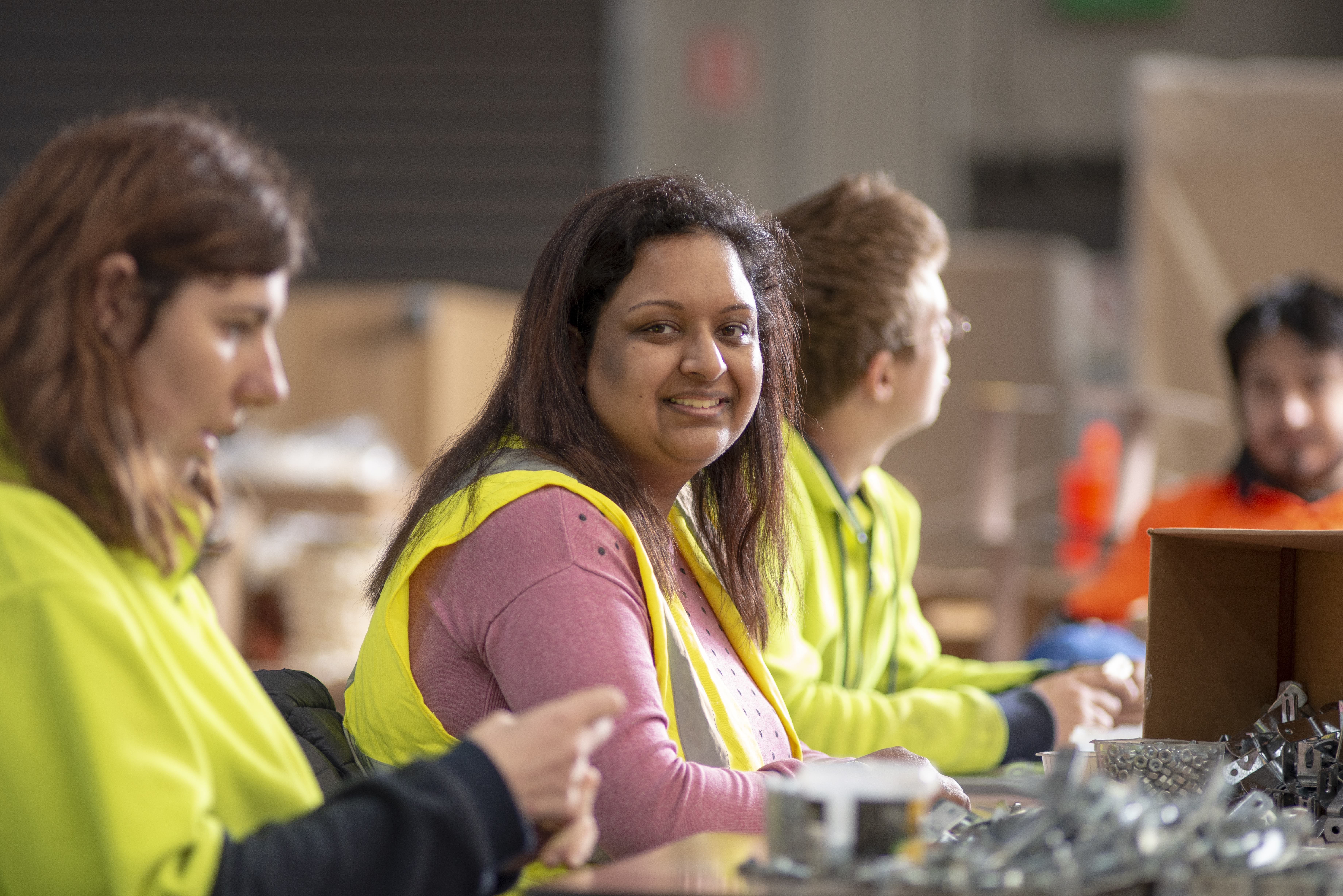 Trainees seated at a table in the warehouse packing items.