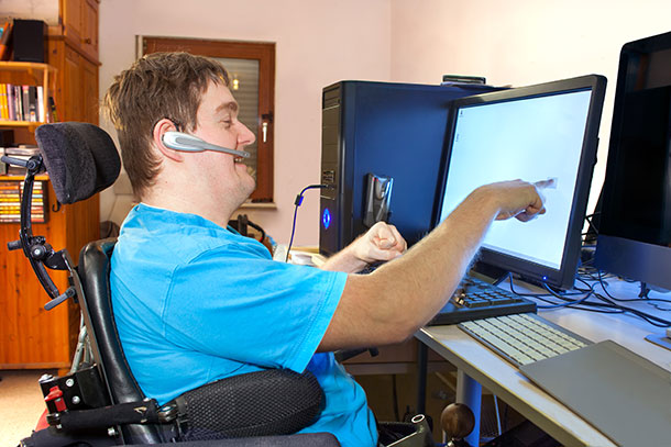 Man with Cerebral Palsy using assistive technology to work on a computer