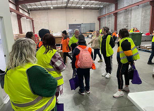 A group of people in high vis vests walk through a warehouse