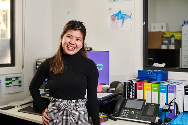 Patricia stands in the reception office, she is smiling