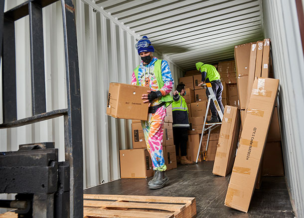 Three people are unloading a shipping container