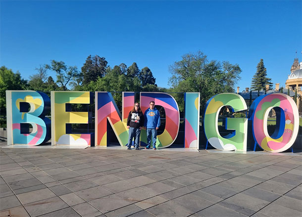 Scott and Alice stand in front of giant colourful letters spelling out BENDIGO