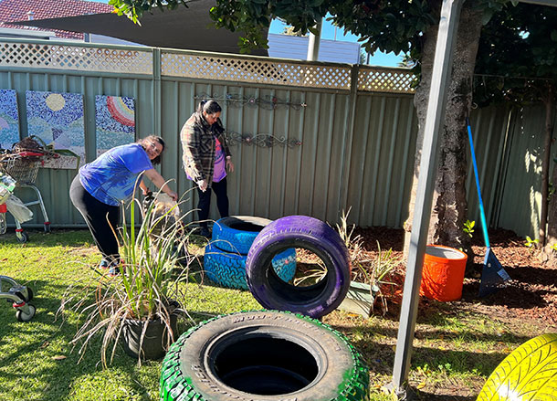 People arrange colourful tyre planters in the garden