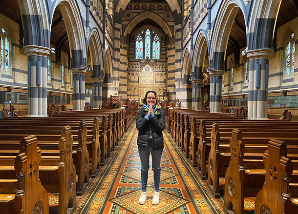 Shakaya stands inside St Paul's Cathedral, she is pressing her palms together and smiling