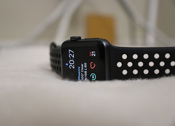 A smart watch with a display showing the time, weather and heart rate