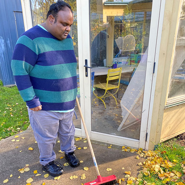 A man sweeps up leaves outside