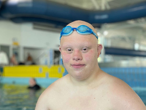 A man is in the pool. he is wearing goggles on his head