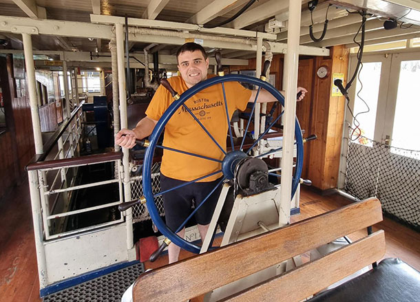 Thomas is standing at the ship's helm holding the wheel