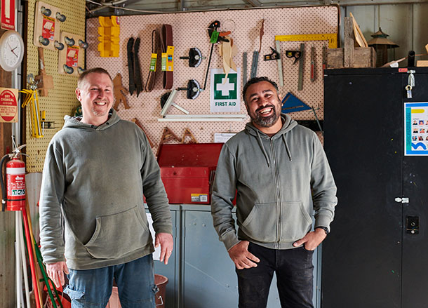 Two Mambourin facilitators stand side by side smiling in a woodwork shed
