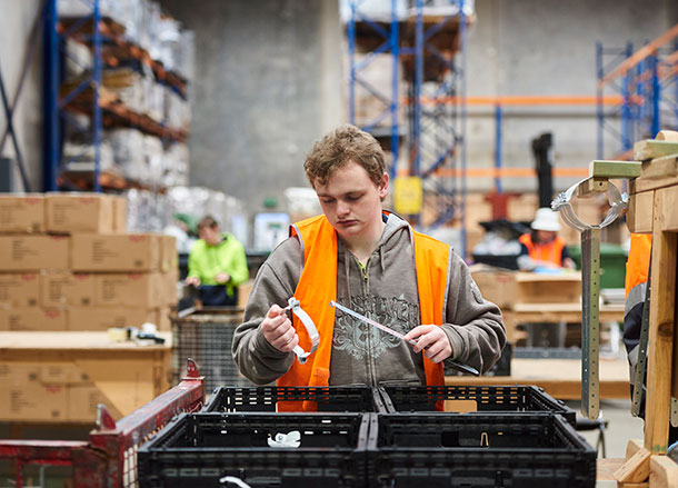 A young man is working at an assembly station in a warehouse