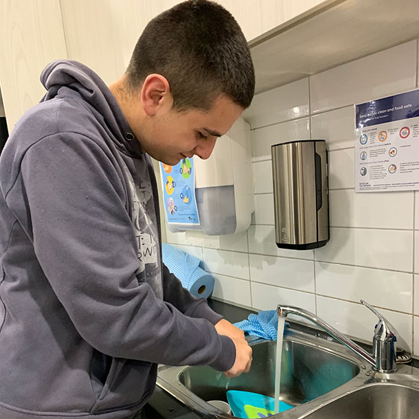A man is standing at the sink washing dishes