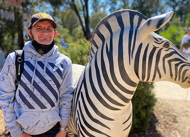 A man stands outside beside a zebra statue