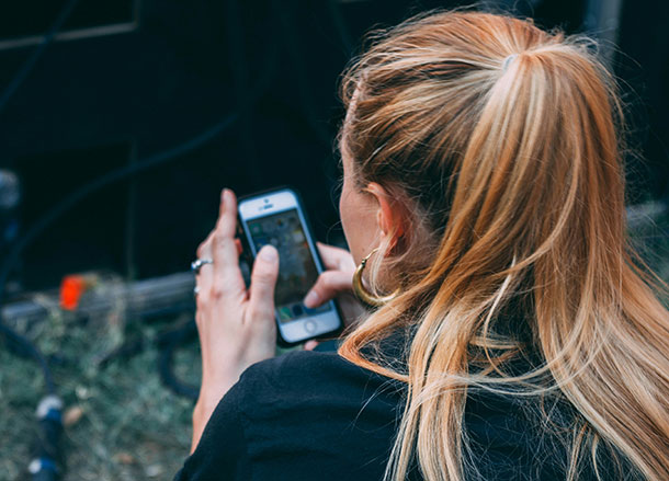 A woman is holding a mobile phone in her hands in front of her