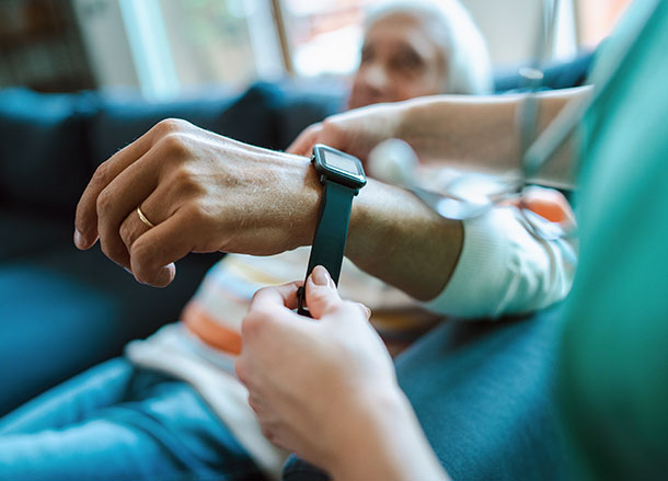 A medical professional straps a smart watch onto a man's wrist