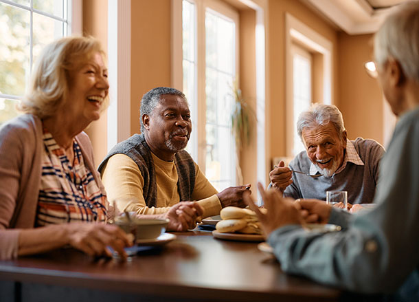 Four older people sit around a cafe table talking and laughing