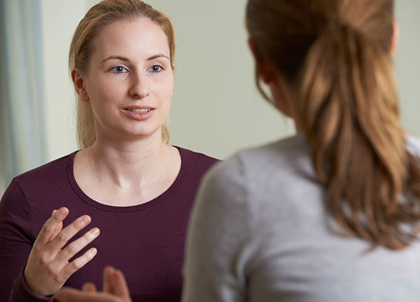 A woman is talking to another woman who is facing her
